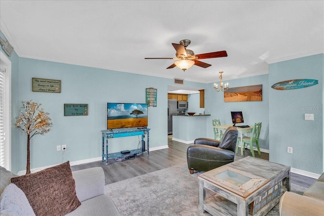 living room featuring ceiling fan with notable chandelier, wood finished floors, visible vents, baseboards, and crown molding