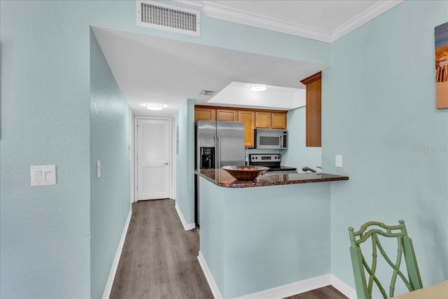 kitchen with stainless steel appliances, brown cabinets, visible vents, and baseboards