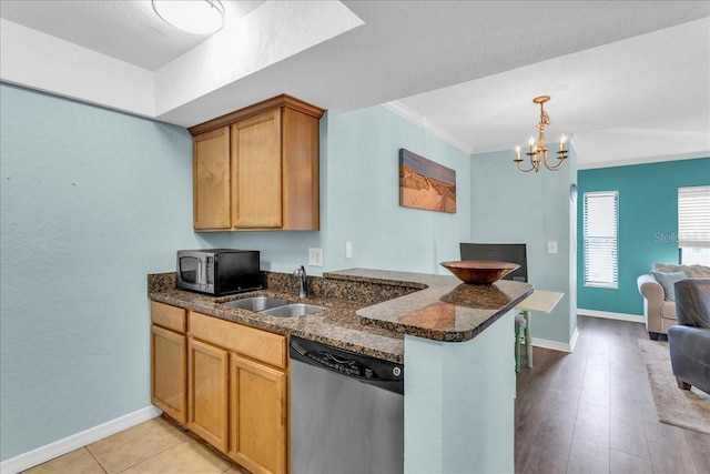 kitchen with a peninsula, a sink, open floor plan, appliances with stainless steel finishes, and dark stone countertops