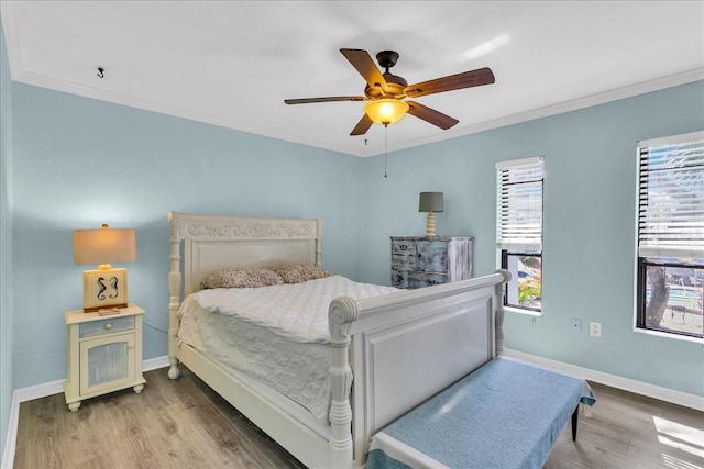 bedroom with ornamental molding, a ceiling fan, baseboards, and wood finished floors