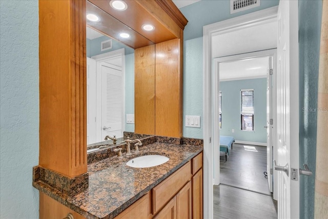 bathroom featuring baseboards, visible vents, wood finished floors, and vanity