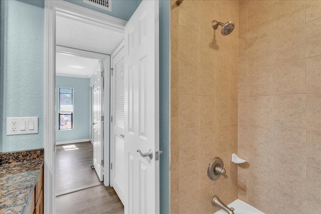 full bath featuring shower / bath combination, wood finished floors, visible vents, and baseboards