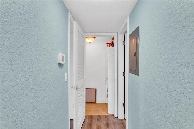 hall with electric panel, a textured wall, and wood finished floors