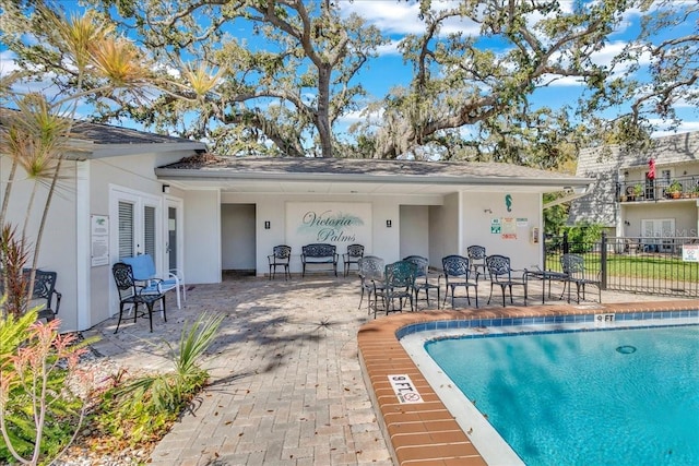 pool with french doors, a patio area, and fence