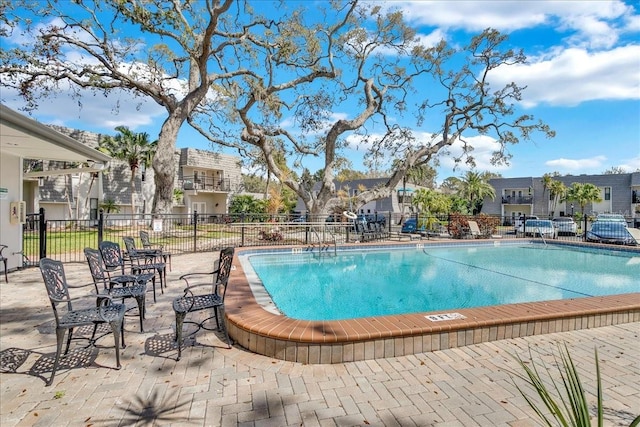 pool with a residential view, fence, and a patio