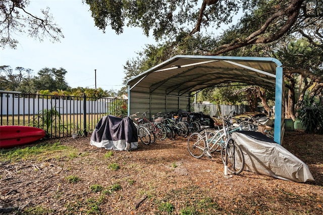 view of parking with fence and a detached carport