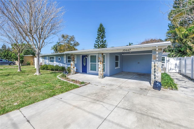 ranch-style house featuring fence, a front lawn, a carport, and concrete driveway