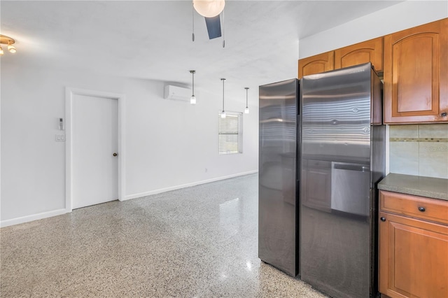 kitchen with brown cabinetry, baseboards, light speckled floor, and freestanding refrigerator