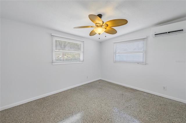 empty room with a wall mounted air conditioner, a ceiling fan, and baseboards