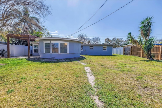 rear view of property with a fenced backyard, a yard, and stucco siding