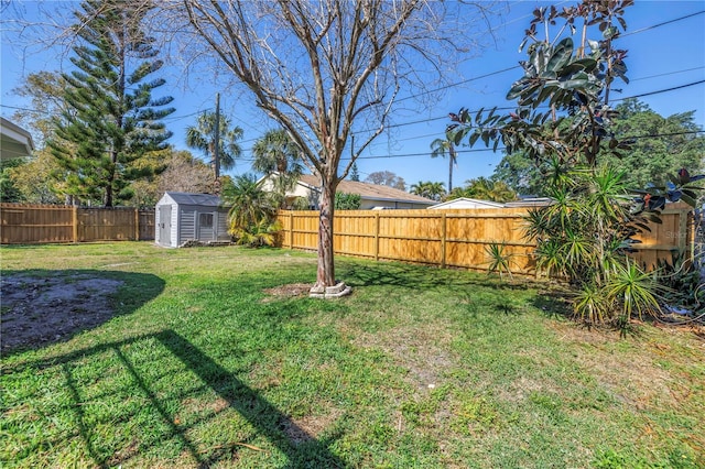 view of yard featuring a shed, a fenced backyard, and an outbuilding