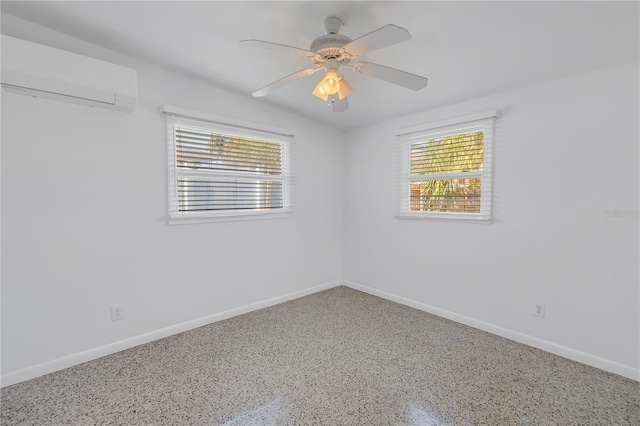 unfurnished room featuring speckled floor, a wall mounted AC, and baseboards