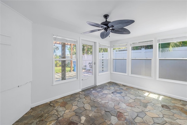 unfurnished sunroom featuring ceiling fan and a wealth of natural light