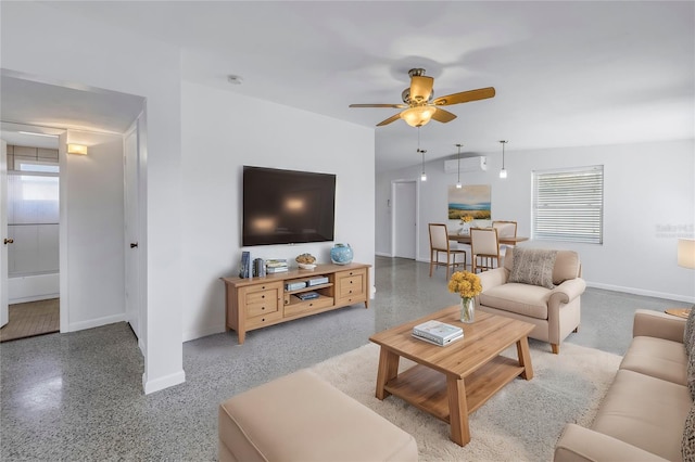 living area featuring ceiling fan, speckled floor, and baseboards