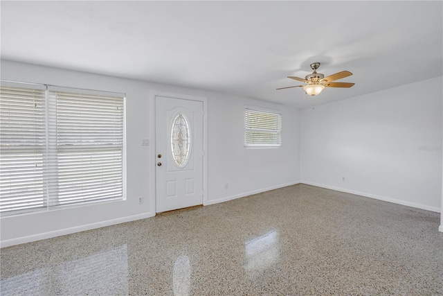 entryway with speckled floor, a ceiling fan, and baseboards