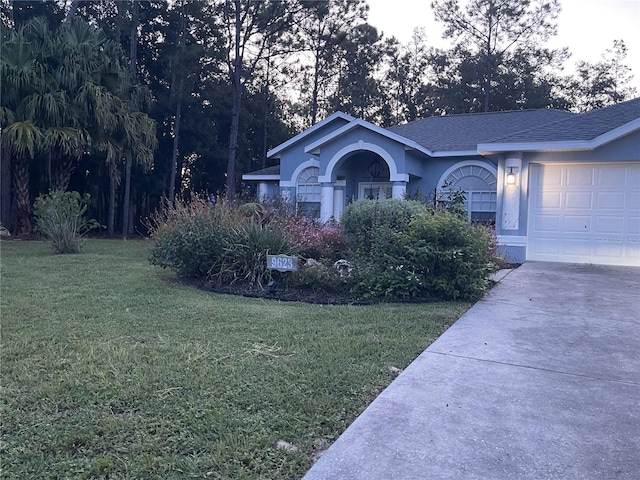 view of front of house featuring a shingled roof, concrete driveway, an attached garage, a front yard, and stucco siding