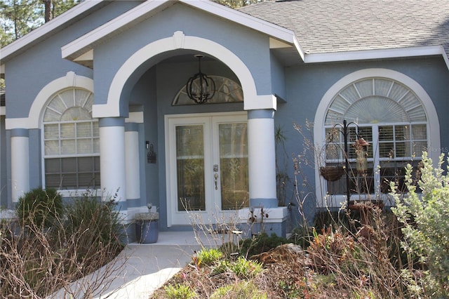 doorway to property with french doors, roof with shingles, and stucco siding