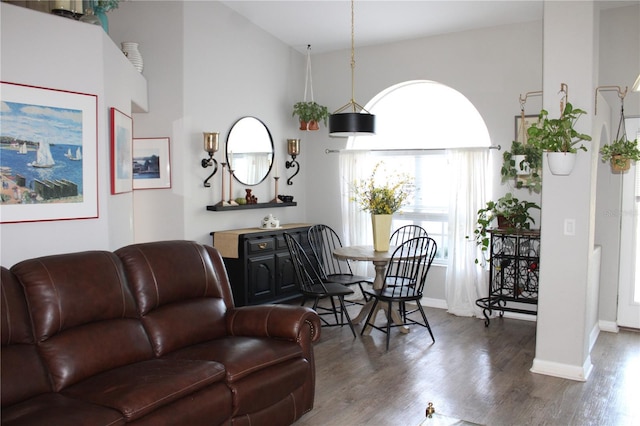 living room featuring high vaulted ceiling, baseboards, and wood finished floors