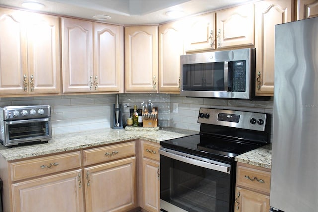 kitchen with light stone counters, a toaster, stainless steel appliances, decorative backsplash, and light brown cabinetry