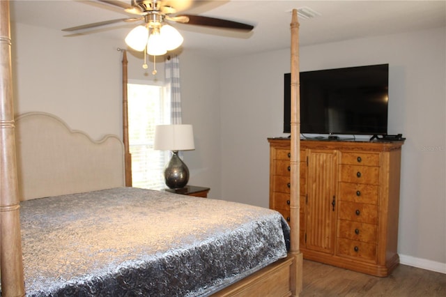 bedroom featuring baseboards, ceiling fan, visible vents, and wood finished floors