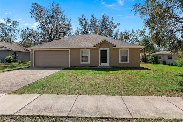 ranch-style home featuring stucco siding, an attached garage, decorative driveway, central air condition unit, and a front yard