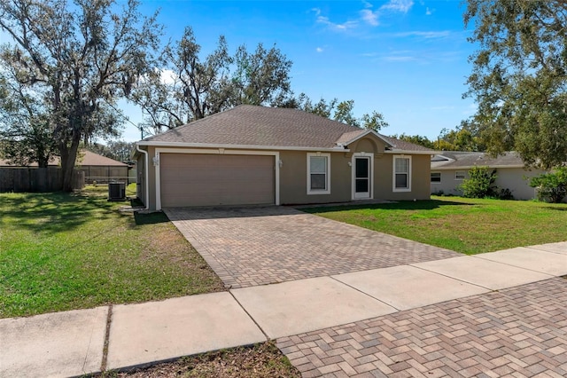 single story home with an attached garage, decorative driveway, a front yard, and fence