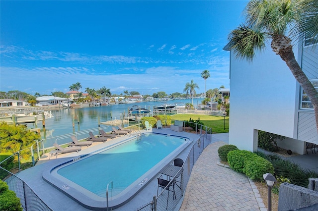 community pool with a dock, a water view, fence, and a patio