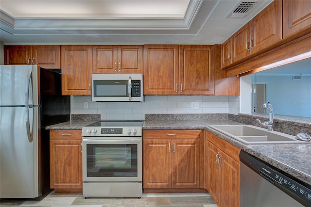 kitchen with appliances with stainless steel finishes, brown cabinets, a sink, and visible vents