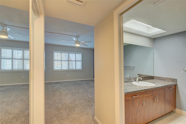 bathroom with a skylight, visible vents, baseboards, ceiling fan, and vanity