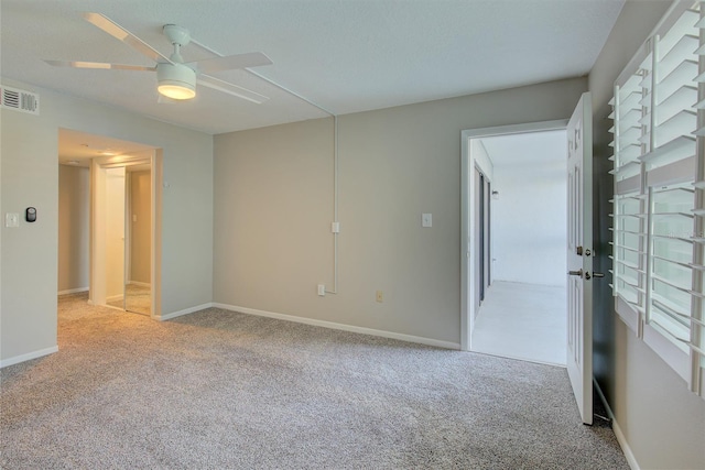 empty room with a ceiling fan, light carpet, visible vents, and baseboards