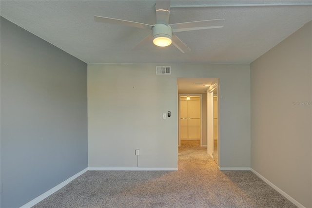 carpeted empty room featuring visible vents, a textured ceiling, and baseboards