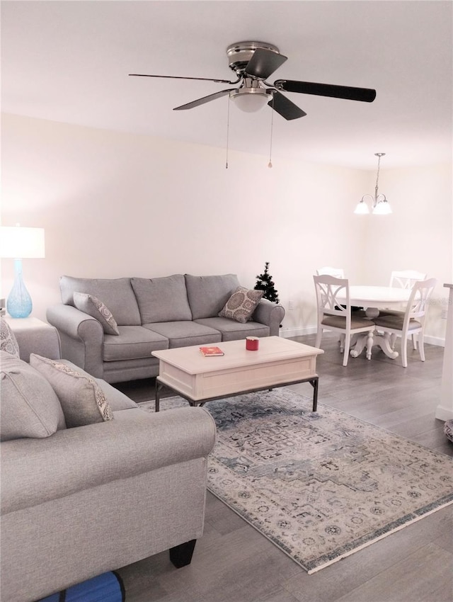 living area featuring ceiling fan with notable chandelier and wood finished floors