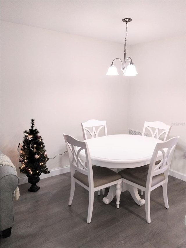 dining space featuring a notable chandelier, baseboards, and wood finished floors