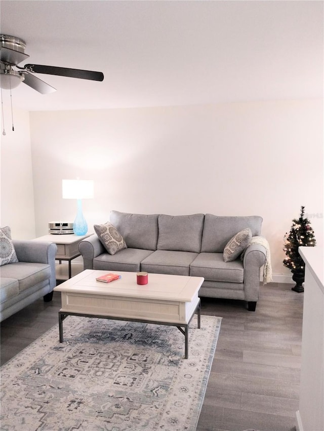 living room with ceiling fan, baseboards, and wood finished floors