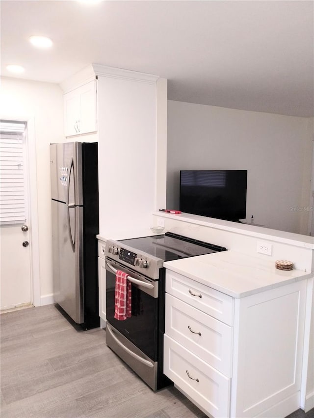 kitchen featuring light wood-type flooring, a peninsula, appliances with stainless steel finishes, and light countertops