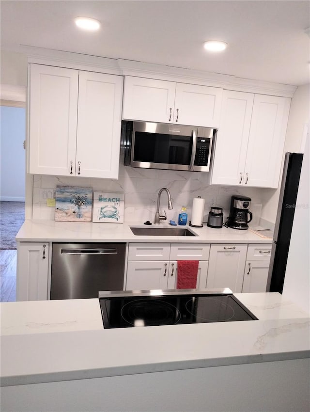 kitchen with white cabinetry, appliances with stainless steel finishes, decorative backsplash, and a sink