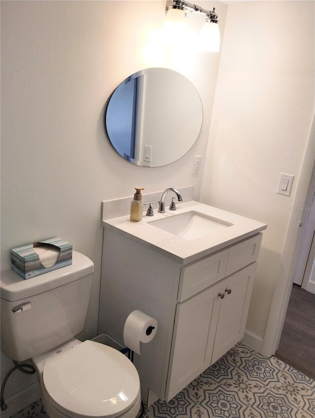 half bathroom featuring toilet, tile patterned flooring, and vanity