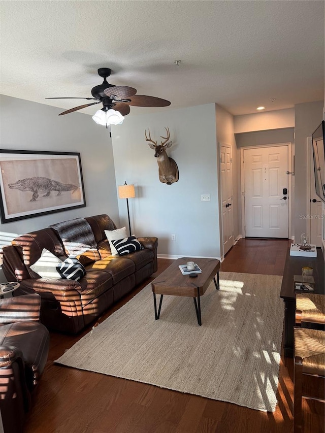 living room featuring dark wood-style floors, ceiling fan, and a textured ceiling