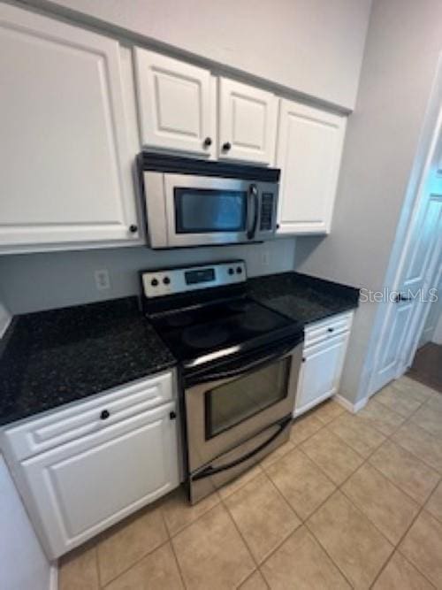 kitchen with white cabinets, light tile patterned floors, baseboards, and stainless steel appliances