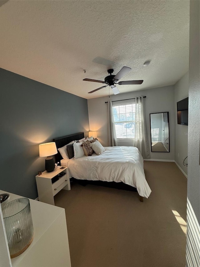 carpeted bedroom featuring ceiling fan, a textured ceiling, and baseboards