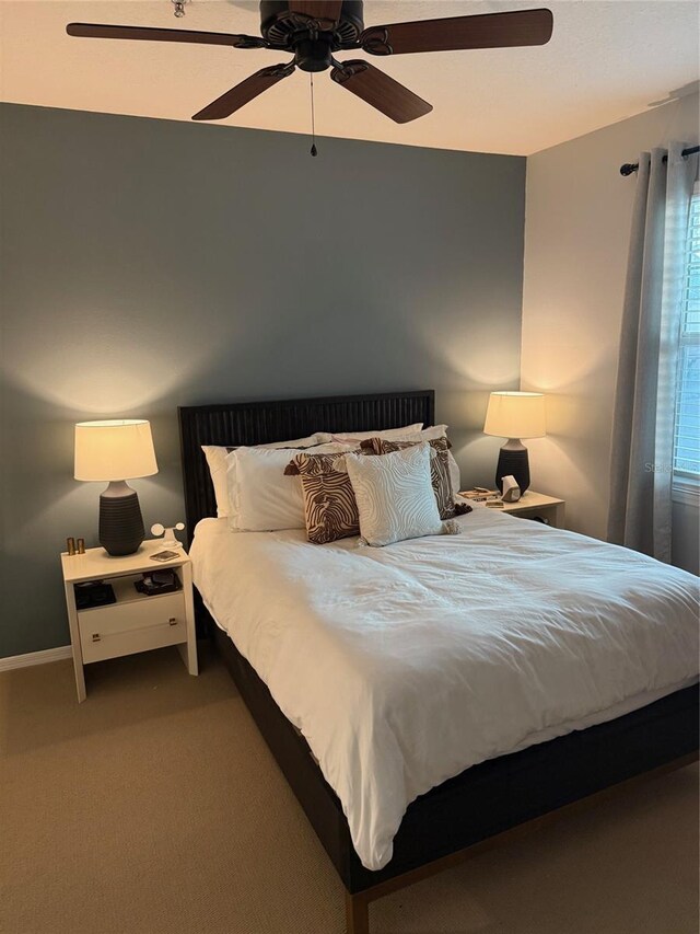 bedroom with a ceiling fan, carpet flooring, and baseboards