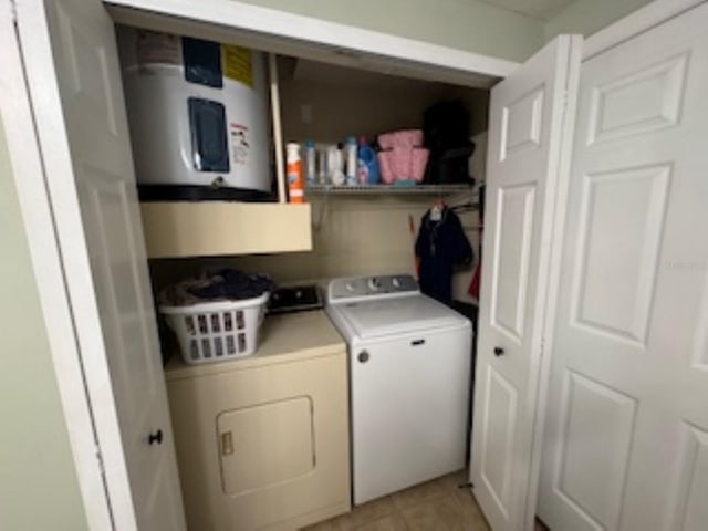 clothes washing area with water heater, laundry area, separate washer and dryer, and light tile patterned floors