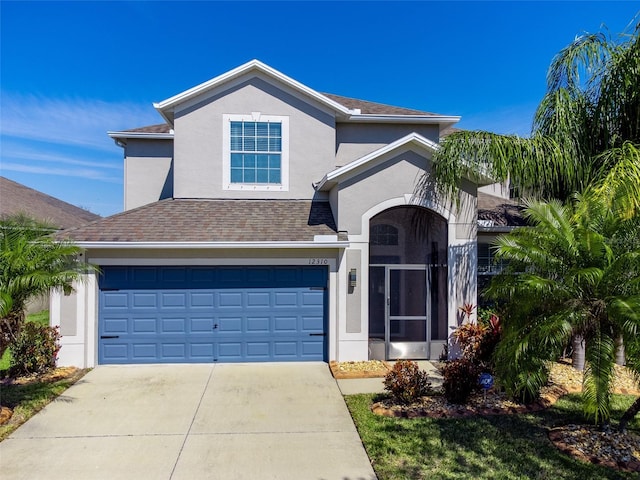 traditional-style home with roof with shingles, driveway, an attached garage, and stucco siding