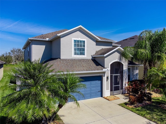 traditional-style home featuring a shingled roof, driveway, an attached garage, and stucco siding