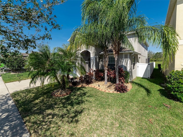 view of front of house with fence, a front lawn, and stucco siding