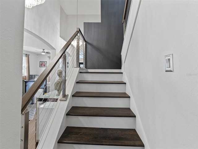 stairs with ceiling fan with notable chandelier