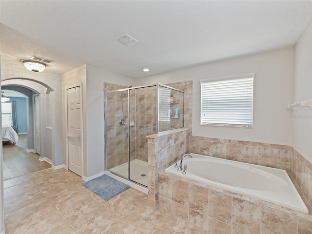 ensuite bathroom featuring a wealth of natural light, a shower stall, ensuite bathroom, and a bath