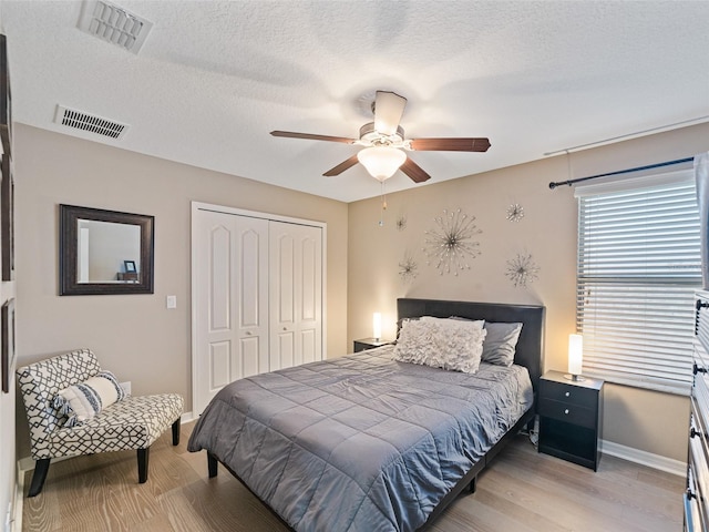 bedroom with a textured ceiling, a closet, visible vents, and light wood-style floors