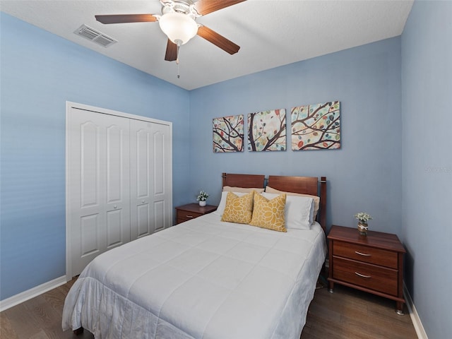 bedroom with a closet, visible vents, baseboards, and wood finished floors