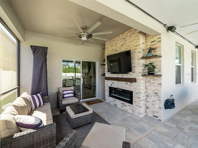 view of patio featuring ceiling fan and an outdoor living space with a fireplace